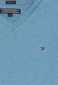 Lichtblauw V-hals t-shirt van biologisch katoen. Heeft een klein geborduurd logo in rood, wit en blauw op de linkerkant van de borst.