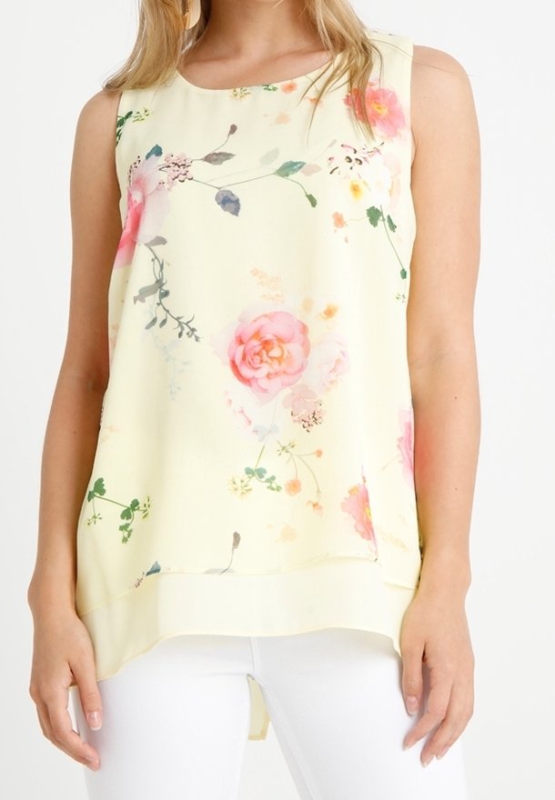 Žlutý top bez rukávů z měkké látky, zdobený květinovými vzory v růžové a zelené barvě. Volný střih s delším zadním lemem.