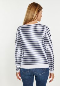 Gestreifter Pullover in Wei�ß und Marineblau, mit Rundhalsausschnitt, langen Ärmeln und geripptem Saum, kombiniert mit blauen Jeans.