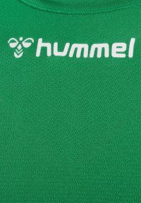 Grünes sportliches Shirt aus strukturiertem Stoff. Verfügt über einen runden Halsausschnitt und ein weißes Logo "hummel" auf der oberen linken Seite.
