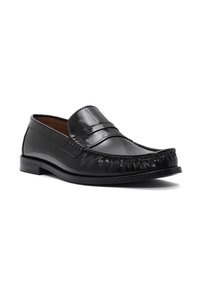 Zwarte leren loafers met een verhoogde gestikte neus, een gladde bovenkant en een gestructureerde franjerand langs de voornaad. Platte rubberen zool.