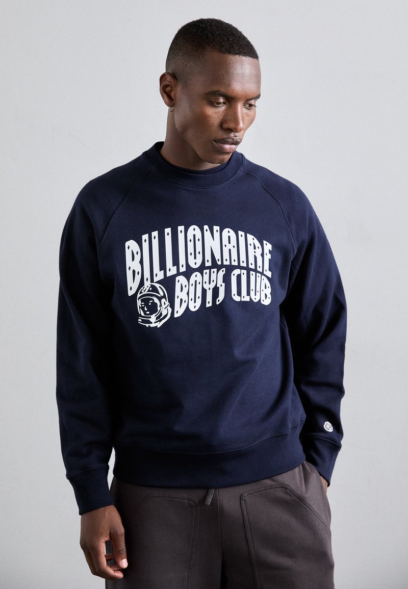 Sweatshirt bleu marine avec le texte blanc "Billionaire Boys Club" et un graphique d'astronaute. Il possède des manches raglan et des poignets côtelés.