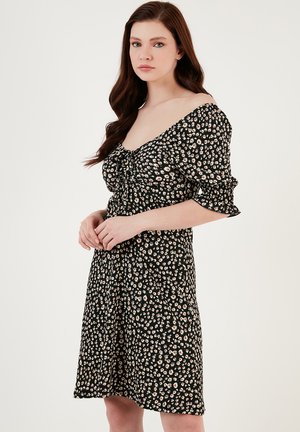 Black floral dress with puffed sleeves, featuring a gathered front detail. Small pink and white flowers against a dark background.