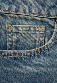 Modra denim tkanina z zadnjo žepom z vidnim šivom, obrabljeno teksturo in svetlejšim obližem blizu zgornjega roba.