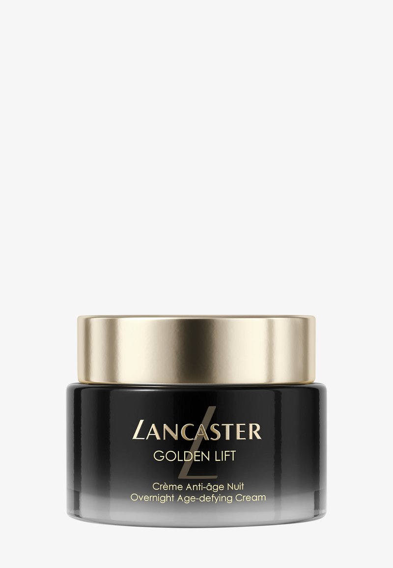 Tarro de vidrio negro con tapa de metal dorado. La etiqueta presenta texto en blanco y dorado; el producto se llama "Lancaster Golden Lift." Crema para uso nocturno.