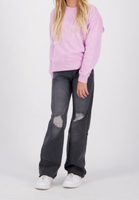 Ljuslila sweatshirt med rundad halsringning och ribbade muddar, tillsammans med grå slitna jeans med hål och vita sneakers.