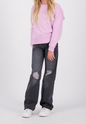 Světle fialová mikina se širokým výstřihem a žebrovanými manžetami, spárovaná se šedými džíny s obnošeným vzhledem obsahujícími díry a bílými teniskami.