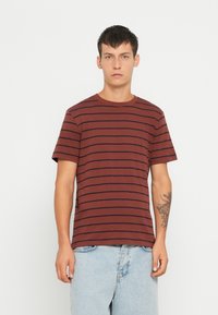 Bordeaux katoenen T-shirt met marineblauwe horizontale strepen. Ronde hals en korte mouwen. Heeft een rechte snit en een ontspannen pasvorm.