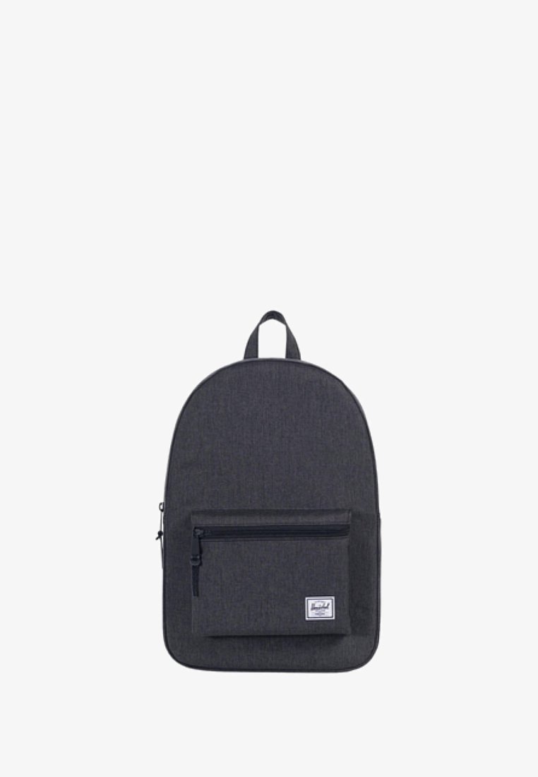 Mochila de tela gris con forma redondeada, que cuenta con un bolsillo frontal con cremallera y un asa en la parte superior para su transporte. Diseño simple, sin patrones ni acentos.