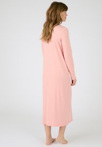 Indossare una lunga camicia da notte rosa a coste con maniche lunghe, orlo scallop e texture morbida, che arriva a metà polpaccio.