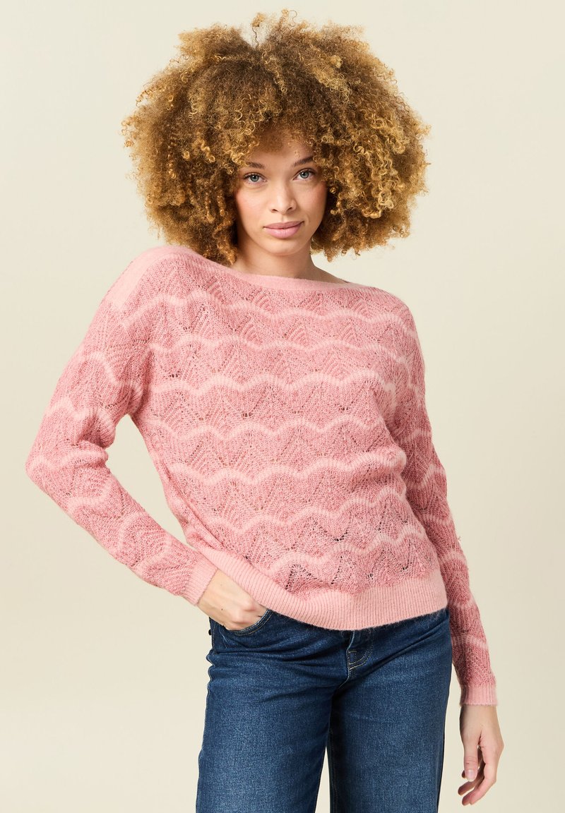 Rosa gestrickter Pullover mit wellenförmigem Muster, lockerer Passform und gerippten Bündchen. Die Textur wirkt weich und das Design ist leicht.