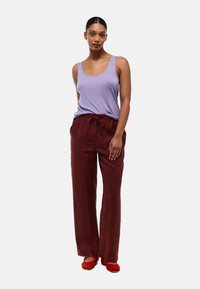 Débardeur violet clair associé à un pantalon bordeaux ample avec cordon de serrage, et ballerines rouges. Tissu doux avec une coupe décontractée.