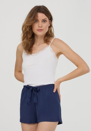 Camisola bianca con rifiniture in pizzo abbinata a pantaloni navy con vita elastica e dettaglio in cravatta. Tessuto morbido, vestibilità comoda.