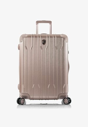 Valigia rigida in oro rosa metallizzato, con scanalature verticali, manico estraibile e quattro ruote girevoli per una facile manovrabilità.