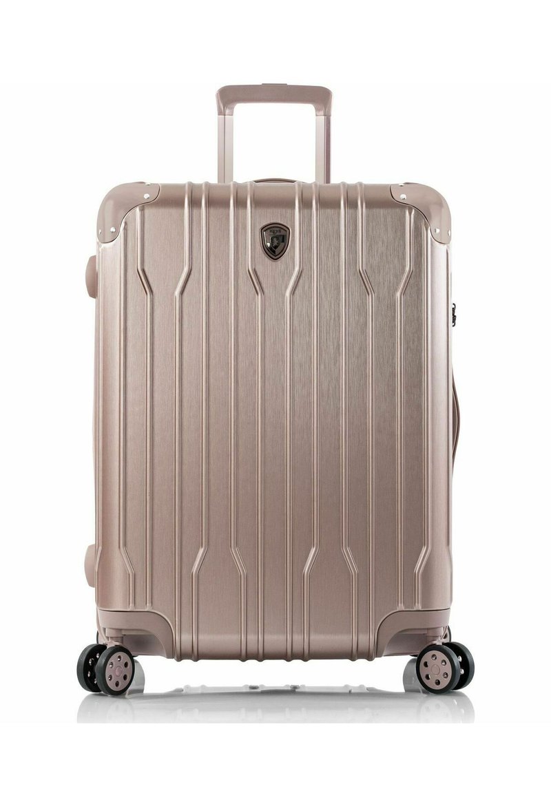 Valigia rigida in oro rosa metallizzato, con scanalature verticali, manico estraibile e quattro ruote girevoli per una facile manovrabilità.