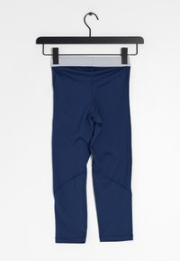 Mörkblå leggings i elastiskt material, med en bred grå midja, knälång klippning och vinklade sömdetaljer. Hänger på en svart krok.
