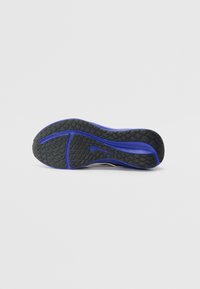 Suola di scarpa sportiva nera e viola con gomma testurizzata, grip a motivo, forma curva e dettaglio del logo Nike in evidenza.
