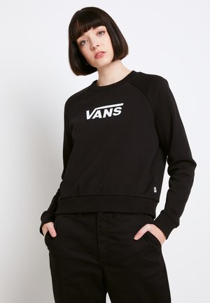 Černá mikina s bílým logem "VANS", s kulatým výstřihem, raglánovými rukávy a pružnými manžetami, v kombinaci s černými kalhotami.