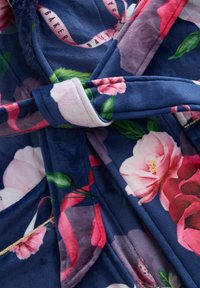 Accappatoio navy con motivo floreale in morbido e lussuoso tessuto. Presenta fiori rosa e rossi con foglie verdi, legato in vita con una cintura coordinata.