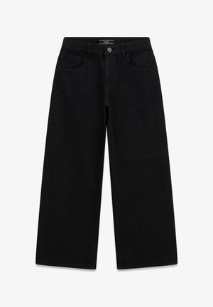 Zwarte jeans met wijde pijpen, voorzakken, riemlussen en knoopsluiting, plat gelegd op een witte achtergrond.