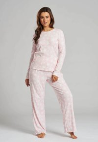 Light pink pajama set featuring long sleeves and relaxed-fit pants, adorned with a star pattern, made from soft, textured fabric.