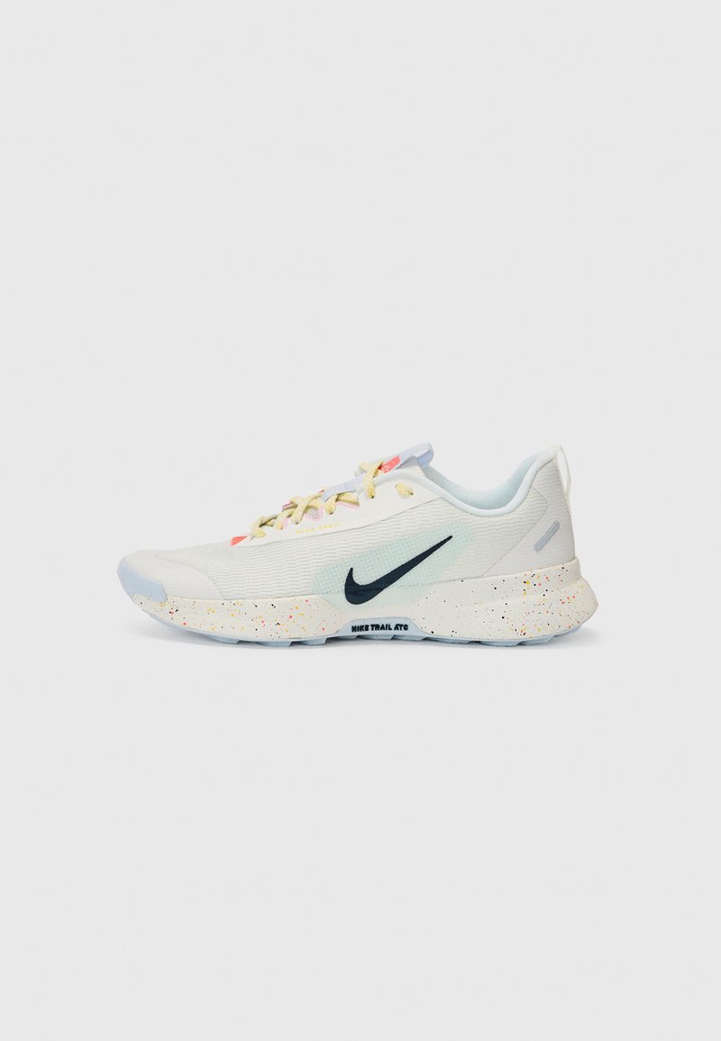 Sapatilha atlética leve e branca com uma superfície texturizada, sola multicolorida salpicada, swoosh da Nike em preto e detalhes em tons pastéis nos atacadores.