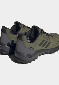 Zelené turistické boty s černými akcenty, síťovinovým a syntetickým materiálem, strukturovaným povrchem a robustní gumovou podrážkou; s označením Gore-Tex.