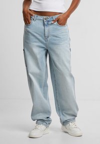 Jeans in denim leggero e morbido, di taglio comodo, con tasche laterali. Il tessuto appare soffice, con una texture leggermente sbiadita. Indossati con sneakers bianche.