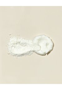 Weißes Pulver und cremige, weiße Substanz auf einem hellbeigen Hintergrund. Das Pulver ist fein-körnig, während die Creme eine glatte, dicke Textur hat.