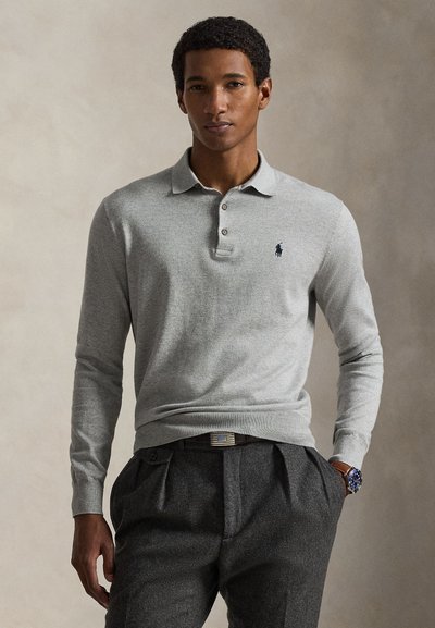 Polo en maille grise avec col, patte à trois boutons et logo brodé sur la poitrine, associé à un pantalon gris foncé sur mesure.