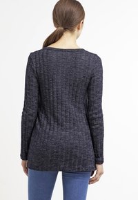 Marineblauwe gebreide trui met lange mouwen, geribbelde textuur en ronde halslijn. Valt losjes, ontworpen voor comfort met een heuplengte snit.