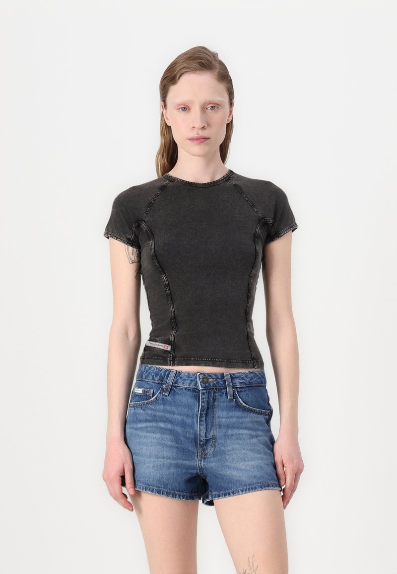 Black short-sleeve fitted shirt with contrasting seams, paired with blue denim shorts. The shirt features a round neckline and is made of cotton blend fabric.