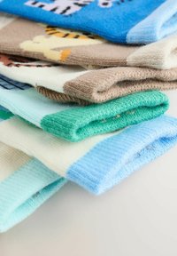 Stapel gefalteter bunter gestrickter Socken mit Tiermustern auf einer weißen Oberfläche.