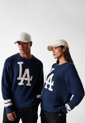 Marine gebreide truien met grote witte "LA" logo's, voorzien van gestreepte manchetten. Beigekleurige baseballcaps met logo-accenten. Getextureerde, relaxte pasvorm.