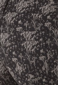Czarna tkanina z bogatym białym wzorem kwiatowym. Posiada subtelną fakturę i zawiera kieszeń z wyszywaniem wzdłuż krawędzi.