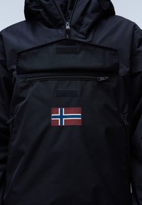 Chaqueta negra impermeable con un gran bolsillo frontal, un zipper vertical y un parche con la bandera noruega en el área del pecho.