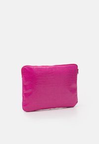 Kirkkaan vaaleanpunainen suorakulmainen pussukka, jossa on krokotiilinsuomuinen pinta ja vetoketjusulku valkoista taustaa vasten.