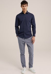 Mornarska srajca z gumbi in dolgimi rokavi, v kombinaciji s svetlimi hlačami s potiskom in belimi supergami. Ozek kroj, gladka tekstura.