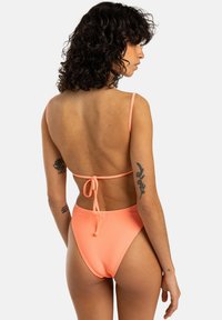 Bikini pêche côtelé avec de fines bretelles ajustables et un dos noué. Présente un design de bas taille haute et une texture lisse.