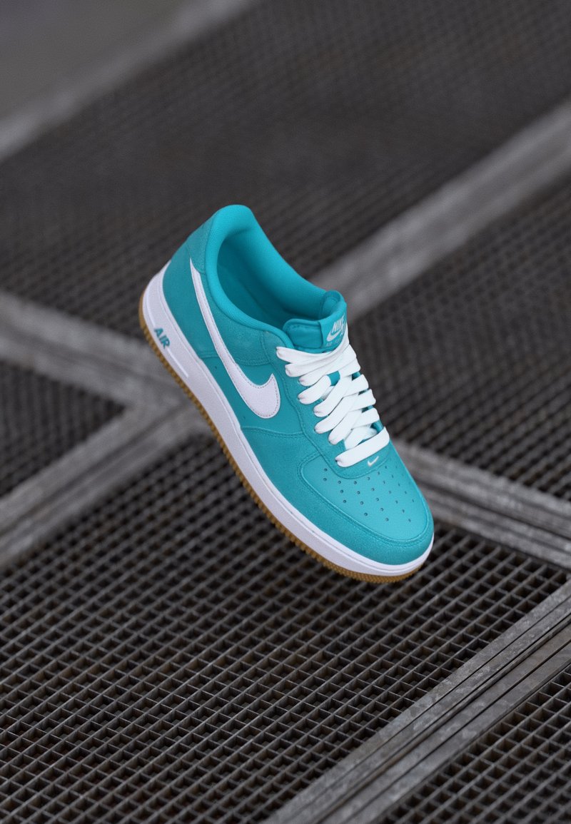 Tyrkysové tenisky Nike Air Force 1 s hladkým koženým zvrškom, bielym logom a šnúrkami a gumovou podrážkou. Perforovaná špička.