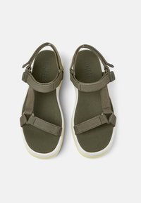 Olivgröna sandaler med justerbara remmar, texturerad sula, rund tå och vita sulor med en lätt gul accent.