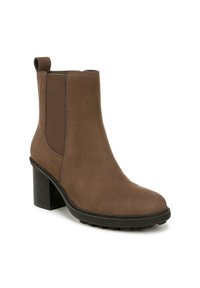 Bottillon en daim marron avec des panneaux élastiques sur les côtés, un bout arrondi et un talon bloc texturé. Le design est élégant avec un minimum de détails.