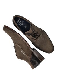 Braune texturierte Schuhe mit Fischgrätenmuster, dunkelbraunen Akzenten, runder Spitze und Holzsohle. Schnürsenkel sind vorhanden, um die Schuhe zu schließen.