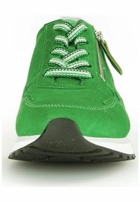 Zapatillas de ante verde con superficie texturizada, media suela blanca en contraste, suela de goma negra y cordones con un patrón en verde y blanco. Detalle de cremallera lateral.
