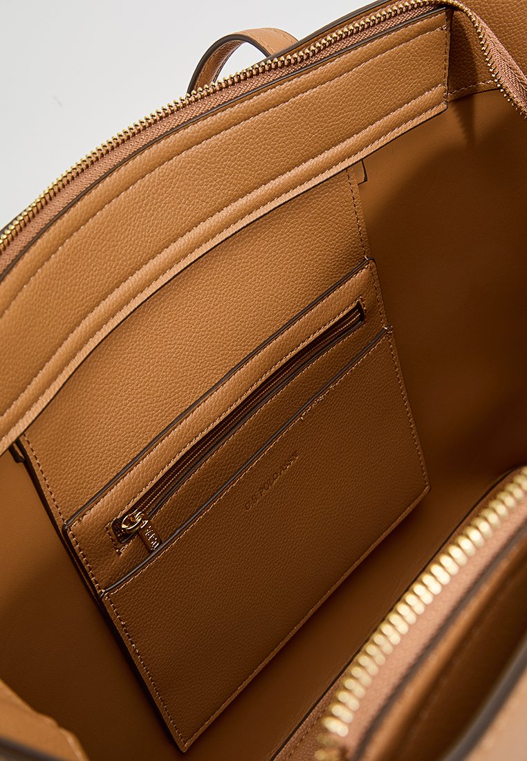 Interno della borsa in pelle beige con una tasca con zip e uno slot per carte, dotato di hardware in tonalità oro e finitura testurizzata.