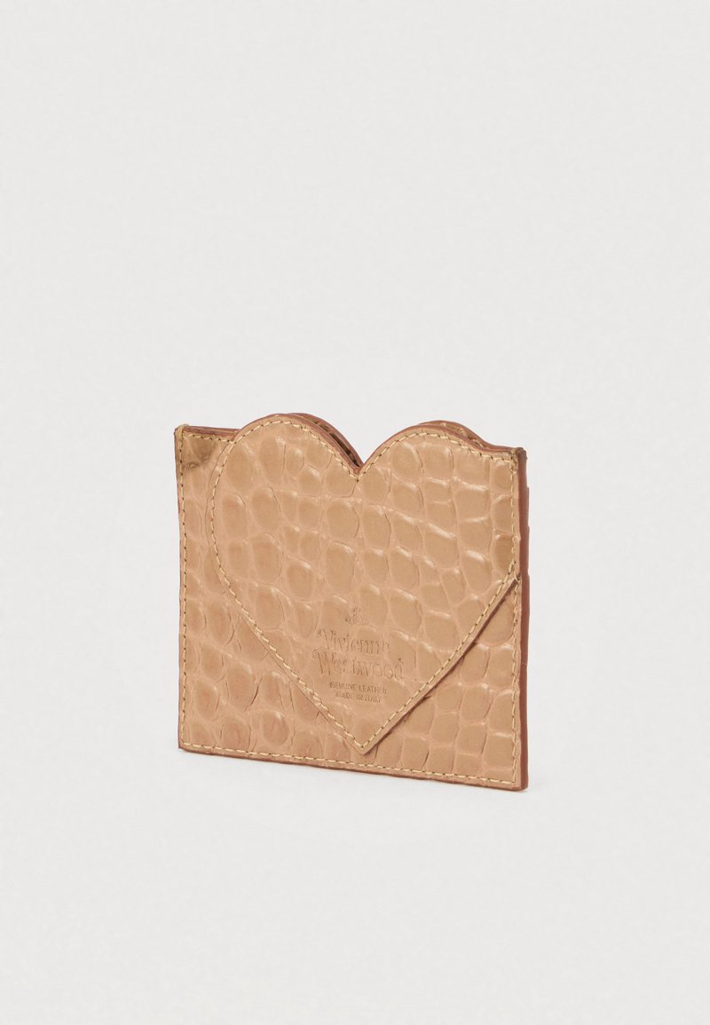 Porta carte in pelle beige con motivo a coccodrillo, chiusura a forma di cuore e cuciture beige. Presenta il logo del marchio impresso sul davanti.