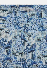 Tissu bleu et blanc à motifs présentant des bâtiments, des balcons, des bateaux et des motifs floraux avec une étiquette Guess taille S.