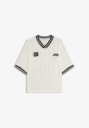 Biely krátky pletený sveter s čiernym pruhovaným V-výstrihom a rukávmi, vyšívané "09" a štýlový text na hrudi.