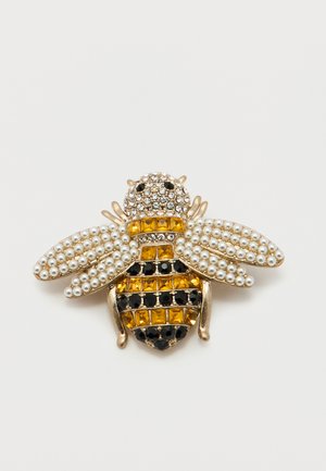 Broša bišu formā ar dzelteniem un melniem dārgakmeņiem ķermenī un pērļu līdzīgiem pērlītēm uz spārniem, iestiprināta zelta tonī metālā.