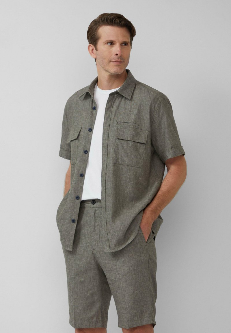 Korte mouw, lichtgrijze button-up shirt met twee borstzakken, gecombineerd met bijpassende shorts. Gladde textuur, casual pasvorm, donkere knopen.